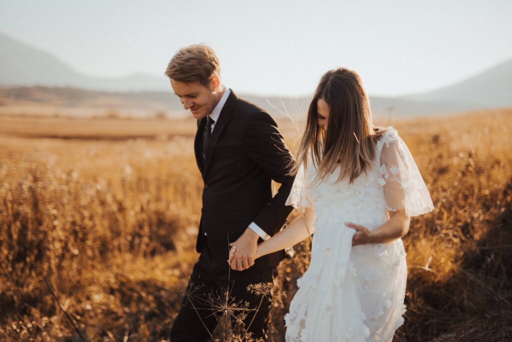 Shallow Focus Photo of Man in Black Formal Suit Holding Woman's Hand in White Dress-Loving Relationship
