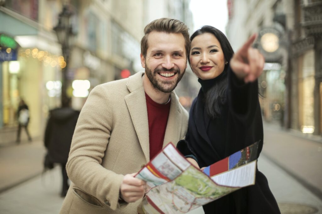 Man in Brown Suit Holding a Map Smiling Beside Woman in Black Coat-Benefits of Bonding Through Shared Experiences