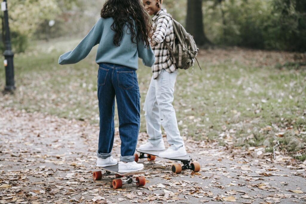 Cheerful diverse same sex couple riding longboards together-Emotional Connection