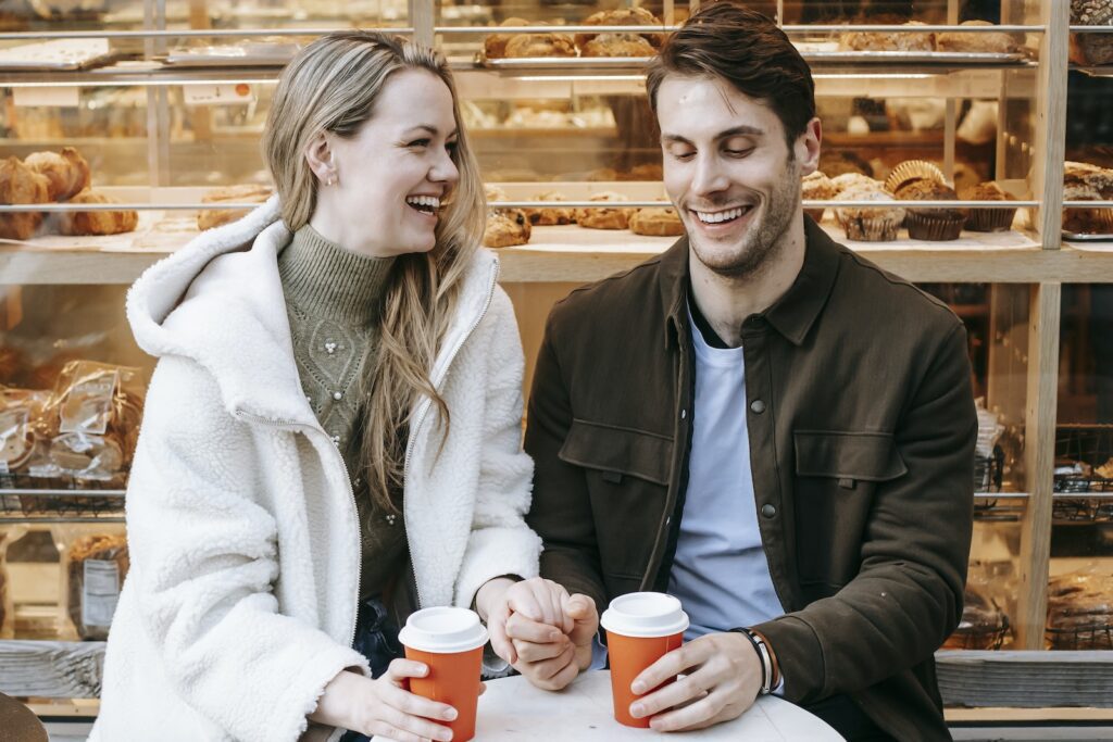 Cheerful young couple holding hands during date in bakery-Interracial Relationship