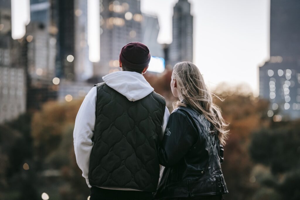 Back view of young couple standing on blurred background of city and enjoying moment-Long-Distance Relationship