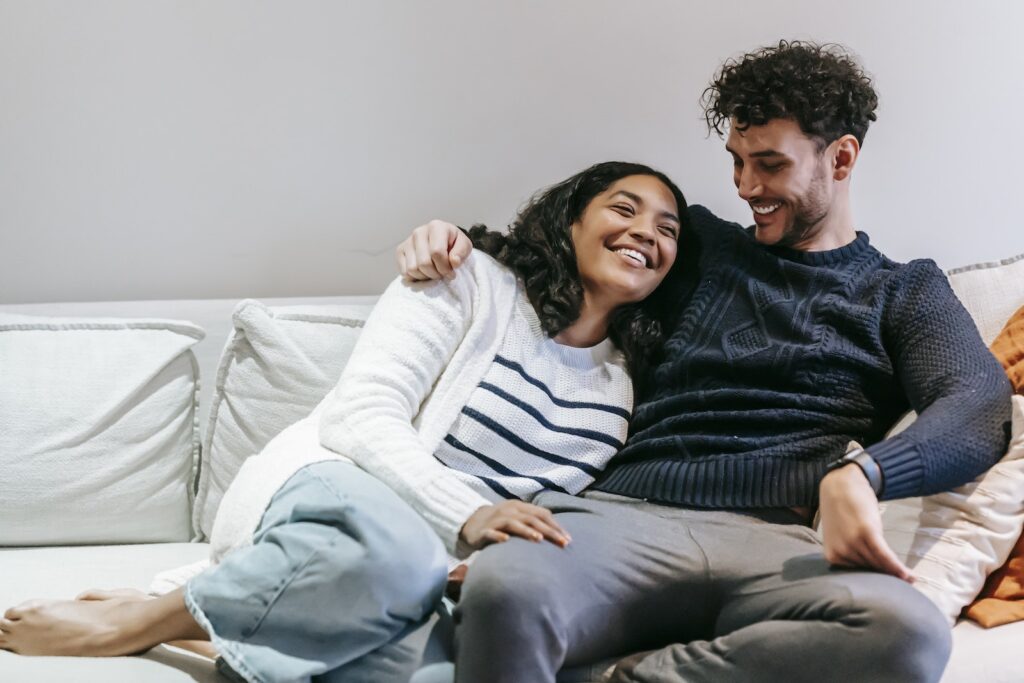 Happy barefoot African American girlfriend with closed eyes and ethnic boyfriend hugging on sofa in cozy living room at home-Love and Appreciation