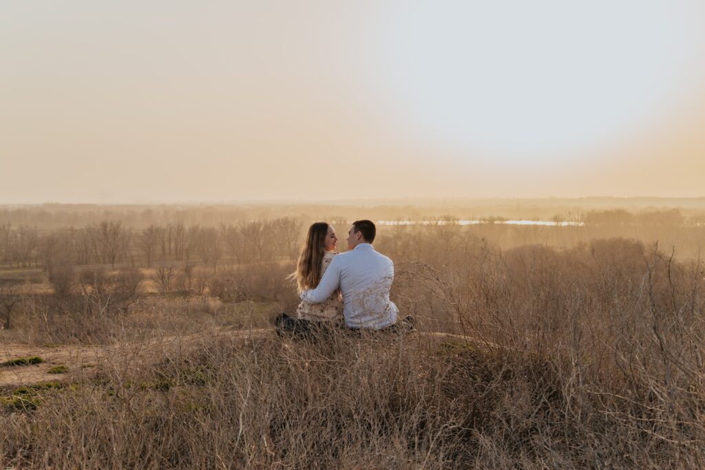 Back view of tender loving couple sitting on hill and hugging while enjoying sunset in nature-Relationship Is Ready for Marriage