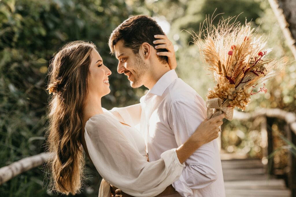 Side view of delightful newlyweds hugging and looking at each other while standing outside on blurred background-Long-Term Committed Relationship