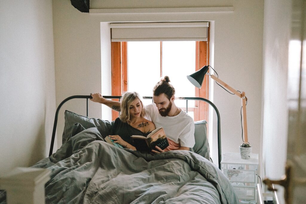man and woman reading book on bed - make your ex-boyfriend miss you