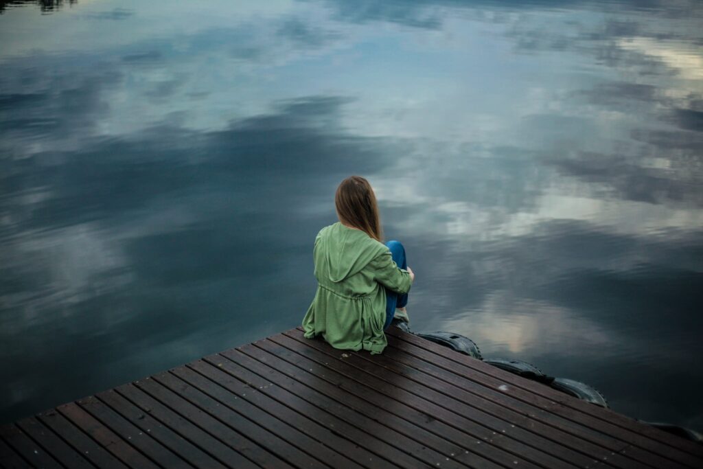 woman sitting on dock near body of water- Stop Liking Your Crush