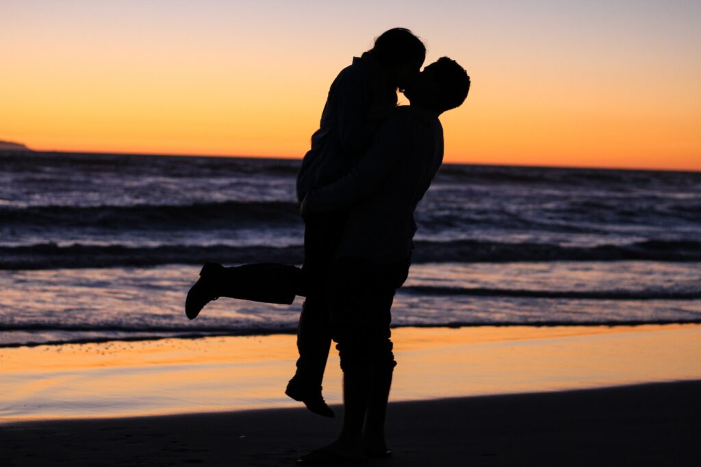 silhouette photo of couple kissing near sea during golden hour - fear of love