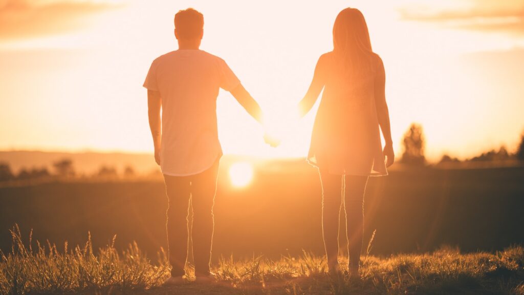 man and woman holding hands white facing sunset- Make Him Miss You