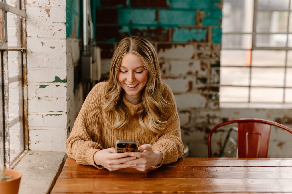 a woman sitting at a table looking at her cell phone-Flirty Texts