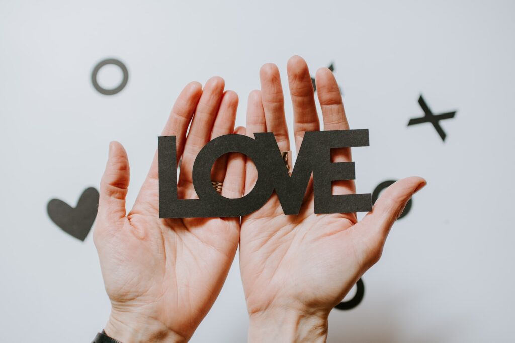person holding love word cutout paper - Shared Experiences