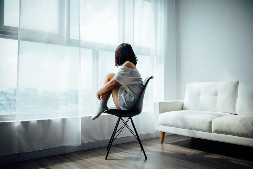 woman sitting on black chair in front of glass-panel window with white curtains- Seeing your ex-boyfriend with someone else