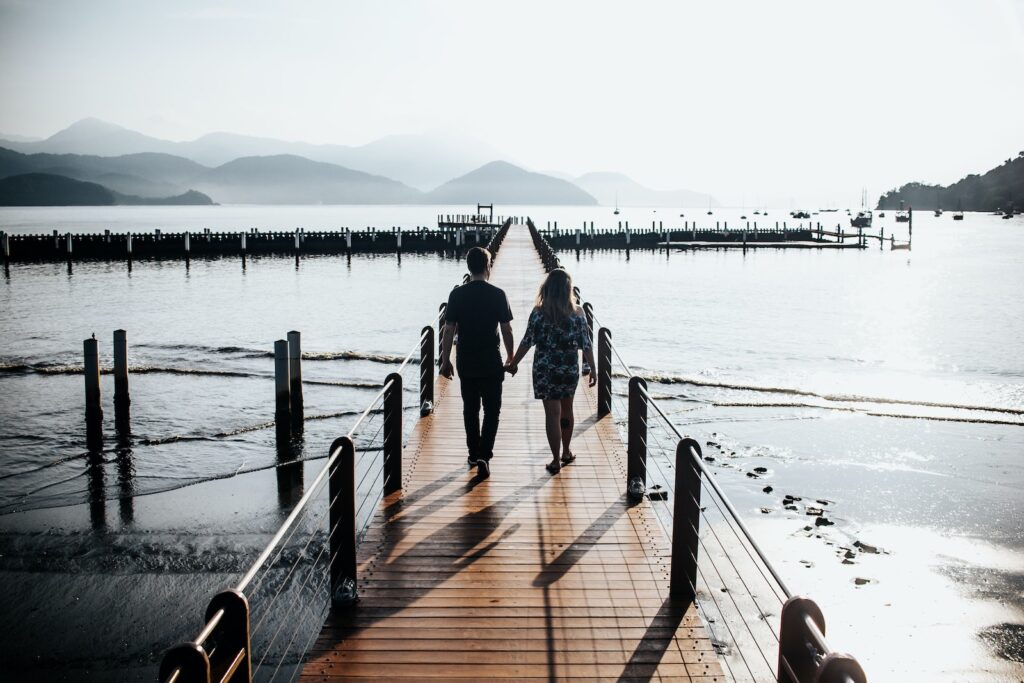 Back View Photo of Couple Holding Hands While Walking Down Wooden Dock-Unlock His Heart