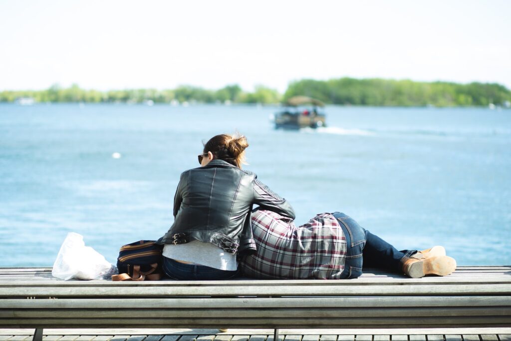 Back view of couple in casual clothes resting on wooden seafront against blue river in park Ready for a Joint Financial Plan