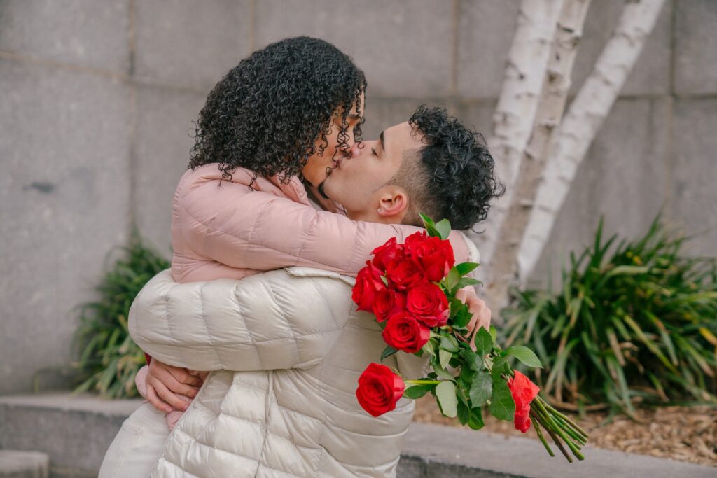 Happy Hispanic woman kissing boyfriend after receiving flowers bouquet Love Overload