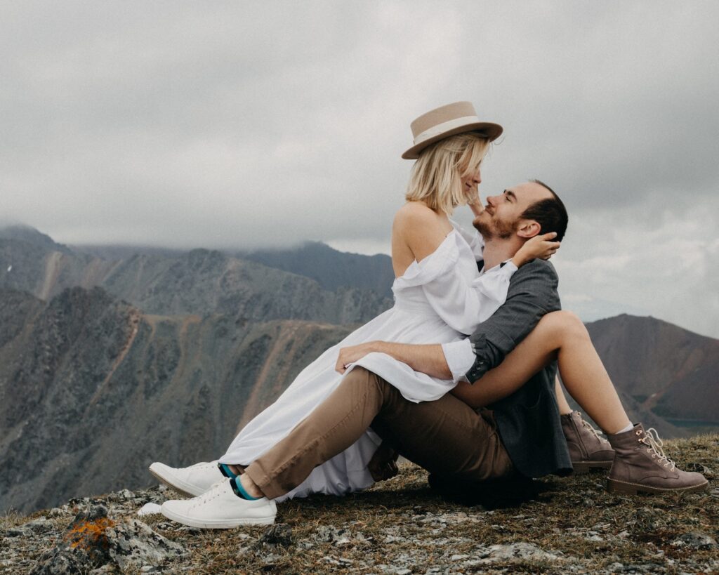 Romantic couple hugging and looking at each other while sitting on mountain Love Overload