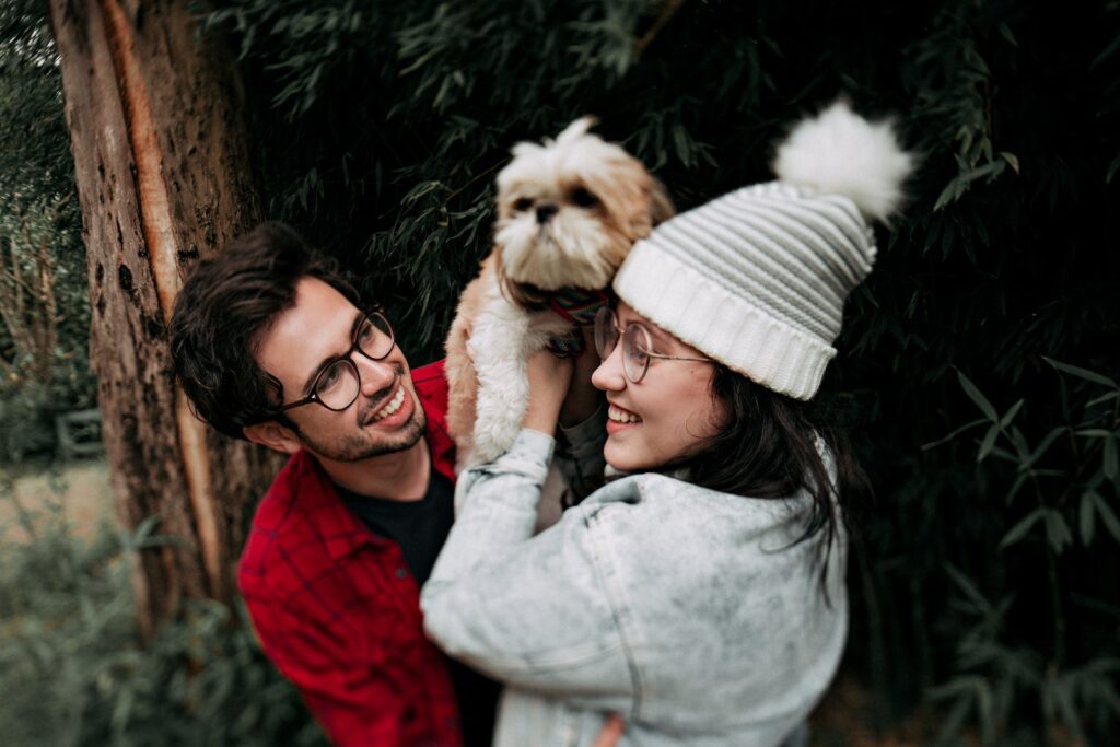 Woman Lifting Puppy in Front of Man Near Tree-Financial Harmony