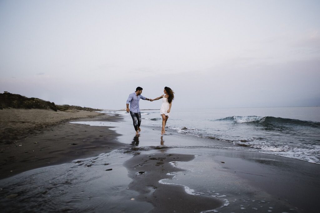 couple, beach, walking-Signs He's Into You