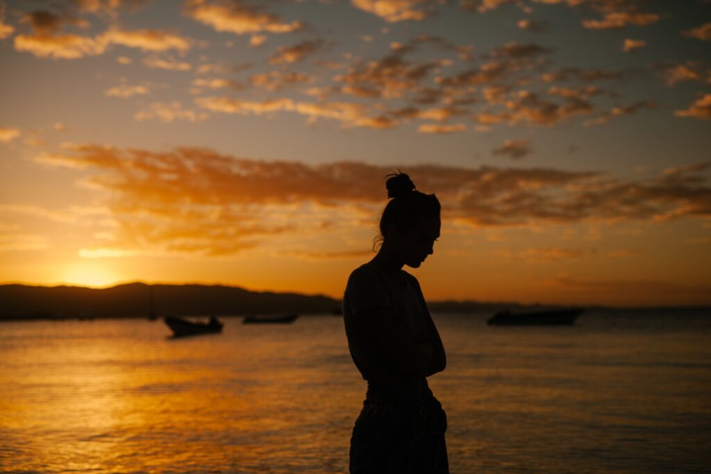 Sad woman standing on coast of sea at sunset-Red Flags