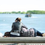 Back view of couple in casual clothes resting on wooden seafront against blue river in park-Bible Say About Supporting Your Spouse