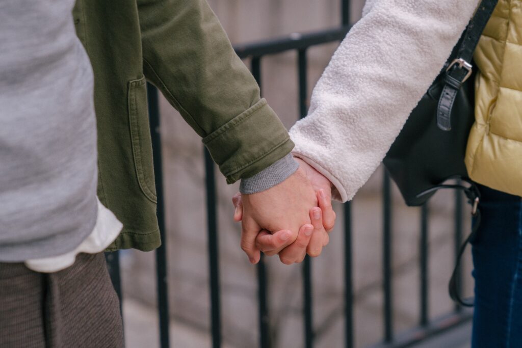 Couple standing near metal fence and holding hands together-Bible Say About Supporting Your Spouse