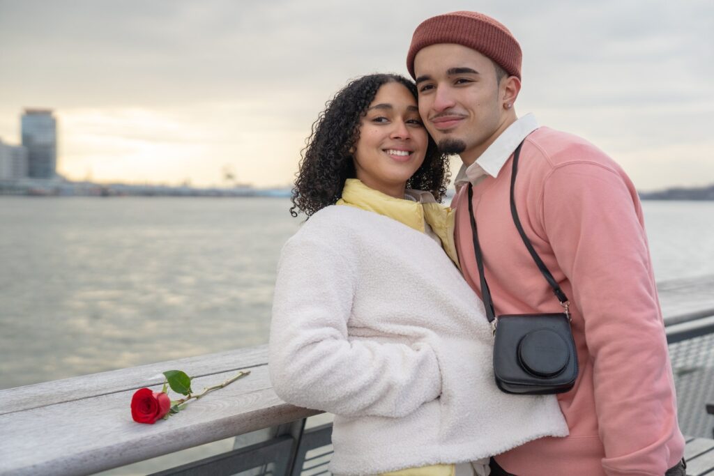 Cheerful Hispanic couple with photo camera looking away while standing near railing on waterfront near sea during romantic date in city-Women Should Look for in a Partner