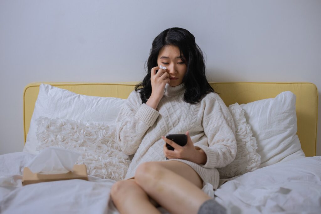 A Sad Woman Looking at her Cellphone While Sitting on a Bed-Common Hurdles to Overcome